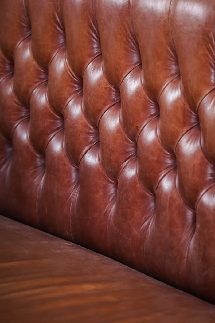 Home Detailed close-up of tufted brown leather upholstery in a vertical shot.