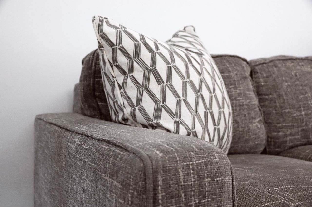 Home Stylish gray sofa with a patterned throw pillow adds elegance to any living space.